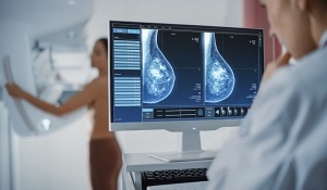 Computer Screen in Hospital Radiology Room: Beautiful Multiethnic Adult Woman Standing Topless Undergoing Mammography Screening Procedure. Screen Showing the Mammogram Scans of Dense Breast Tissues.