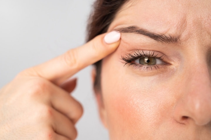 Woman holding her eyelid open